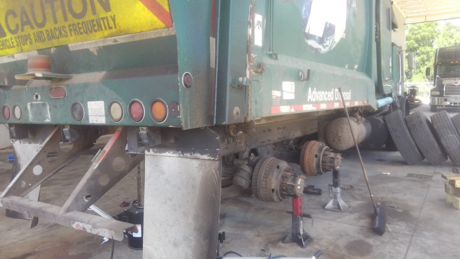 Heavy-duty Mack truck raised on stands for trunnion shaft replacement