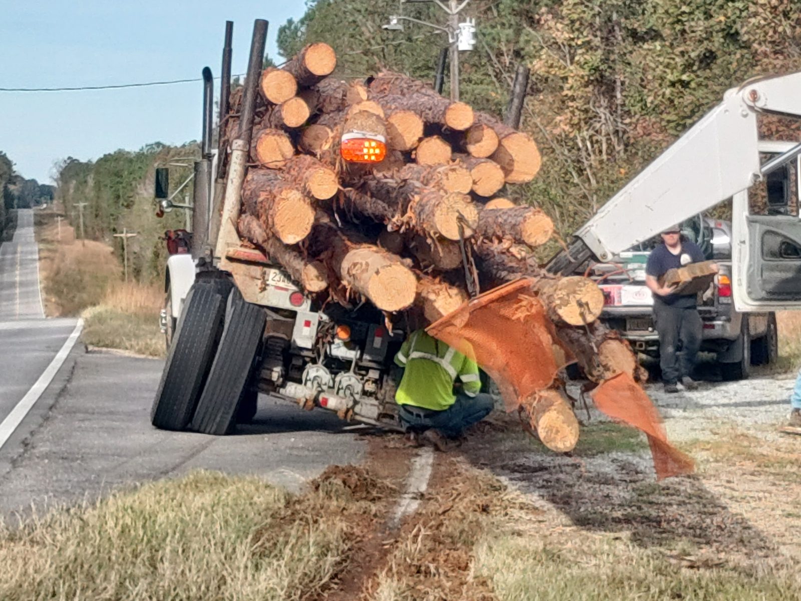 Loaded logging trailer receiving on-site axle spindle repair at the roadside